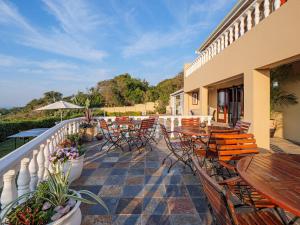 a patio with tables and chairs on a balcony at Umhlanga Beach House in Durban