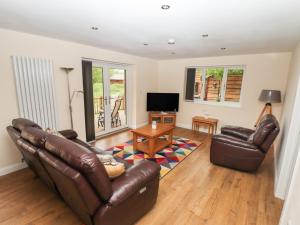 a living room with two leather couches and a television at Butterfly Lodge in Lincoln