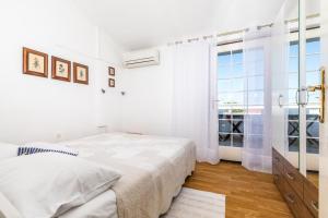 a white bedroom with a bed and a window at Apartmani Nadia in Punat