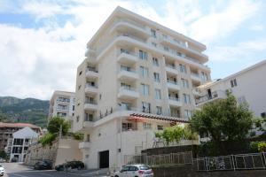 Un edificio blanco con coches aparcados delante. en Apartments Milica, en Bečići