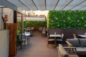 リスボンにあるDinya Lisbon Hotelのテーブルと椅子、緑の壁があるレストラン