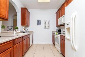 - une cuisine avec des placards en bois et un réfrigérateur blanc dans l'établissement Gorgeous Apartment in Orlando at Vista Cay Resort VC5000, à Orlando