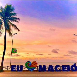 ein Schild an einem Strand mit einer Palme in der Unterkunft Hotel Pousada Alagoana in Maceió