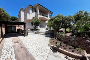 a house with a stone walkway in front of it at Appartamento in villa Porto Pollo in Porto Pollo