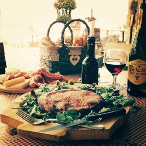 un filete en una tabla de cortar con una copa de vino en Borgo di Corte - alloggio agrituristico, en Prestento