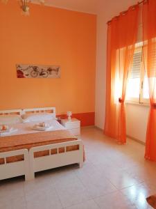 1 dormitorio con paredes de color naranja, 1 cama y ventana en Il sole, en Maruggio