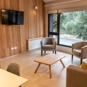 a living room with chairs and a table and a tv at BOG Norway - Departamentos Céntricos in Villa La Angostura