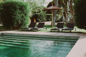 two lounge chairs and an umbrella next to a swimming pool at Hotel Ritual de Terra & SPA in J&aacute;vea