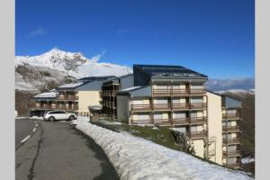 ein Gebäude mit einem auf einer schneebedeckten Straße geparkten Auto in der Unterkunft Appart montagne 3 étoiles Saint-Lary station in Saint-Lary-Soulan