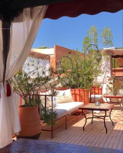 eine Terrasse mit einem Sofa, Tischen und Topfpflanzen in der Unterkunft Riad Andalla in Marrakesch