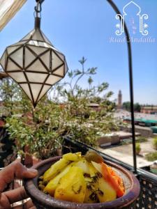 eine Person, die eine Schüssel Essen auf einem Tisch hält in der Unterkunft Riad Andalla in Marrakesch