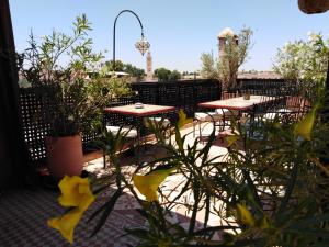 eine Terrasse mit Tischen, Stühlen und Pflanzen in der Unterkunft Riad Andalla in Marrakesch