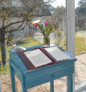 une table bleue avec une plaque et un vase de fleurs dans l'établissement Landhotel Kastanienallee Putbus, à Putbus