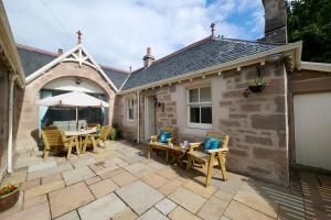 a patio with tables and chairs and an umbrella at Monkland Cottage in Nairn