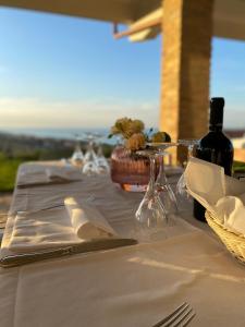 una mesa con mantel blanco y una botella de vino en Casale Adriatico B&B en Pineto