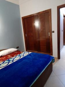 Schlafzimmer mit einem blauen Bett und einem Holzschrank in der Unterkunft دار الضيافة Dar Diafa Essalam in Agadir