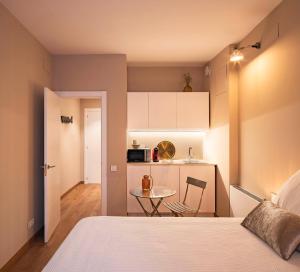 ein Schlafzimmer mit einem Bett und einem Tisch sowie eine Küche in der Unterkunft PassiveRooms in Vilanova i la Geltrú