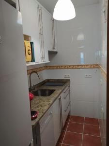 a kitchen with white cabinets and a sink at Sunbeach Malagueta in Málaga