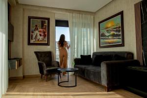 a woman standing in a living room looking out the window at Rozafa Blu Hotel in Shëngjin