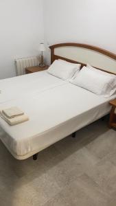 una cama grande con sábanas y almohadas blancas en Aloja Madrid, en Madrid
