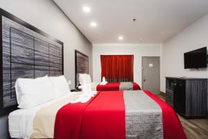 Palace Inn and Suites Baytown في باي تاون: غرفة نوم بسريرين بملاءات حمراء وبيضاء