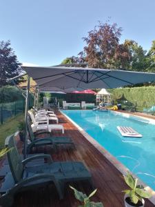 a pool with lounge chairs and a large umbrella at Le domaine de shania in Provenchères-sur-Fave