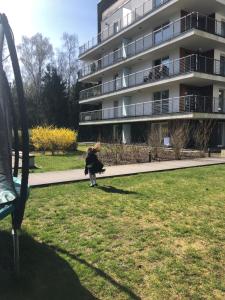 a woman walking in a park in front of a building at Family Apartment Golden Tulip 2 in Międzyzdroje
