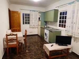 a kitchen with green cabinets and a table with a television at Casa Mary in Valles de Ortega