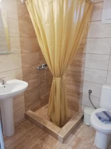 eine Dusche mit Vorhang im Bad mit Waschbecken in der Unterkunft Corner house in Leptokaryá