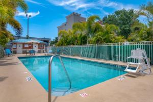 a swimming pool with a chair next to a fence at Comfort Inn & Suites Melbourne-Viera in Melbourne