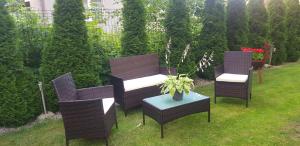 three wicker chairs and a table in a garden at Apartamenty Puk Puk in Mrągowo