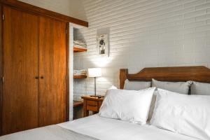 een slaapkamer met een bed met witte lakens en een houten hoofdeinde bij Valeria House Rental Suites in Valeria del Mar