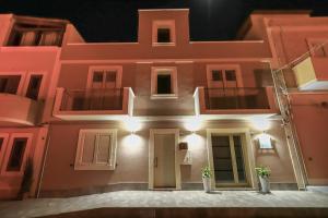 un bâtiment rose avec des lumières allumées la nuit dans l'établissement Domus B&B Le Nereidi, à Lampedusa