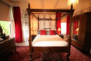 a bedroom with a canopy bed and red curtains at Kingscroft in Buxton