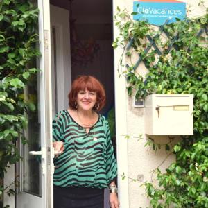 una mujer parada en la puerta de una casa en Chambre d'hôtes chez Claude Bardou en Lacrouzette