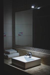 a bathroom with a sink and a large mirror at Estância Avaré Hotel in Avaré