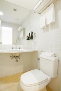 biała łazienka z toaletą i umywalką w obiekcie Golden Tulip Macaé w mieście Macaé