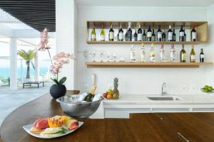 a kitchen with a table with a bowl of fruit and wine bottles at Golden Tulip Macaé in Macaé