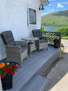 a porch with two chairs and a table and flowers at Alt-an Retreat Lodge overlooking loch linnhe in Fort William