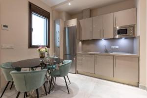 a kitchen with a table and chairs and a refrigerator at BiBo Suites Real Chancilleria in Granada