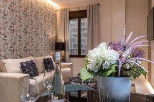 una sala de estar con un jarrón de flores sobre una mesa en BiBo Suites Real Chancilleria en Granada