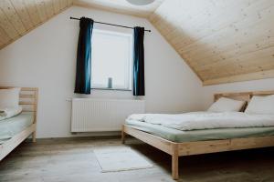 een slaapkamer op zolder met 2 bedden en een raam bij Domki Ciszy Mi Daj in Wisła