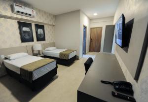 ein Hotelzimmer mit zwei Betten und einem Fernseher in der Unterkunft Bristol Infinity Rio Claro in Rio Claro