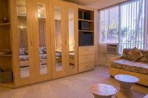 a living room with a large wooden partition with a television at Kuhio Banyan Hotel (with Kitchenettes) in Honolulu