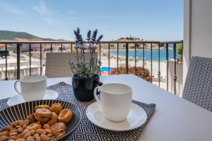a table with two cups of coffee and a plate of donuts at Residence Bepi Malugio in Primošten