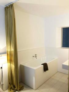 a white bathroom with a tub and a window at Centric Townhouse CADAQUÉS - Casa Voltes - in Cadaqués