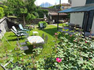 a garden with a table and chairs and roses at Casa Dina in Domaso