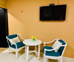 a room with two chairs and a table and a tv at DNA Cancun Hotel y Posada in Cancún