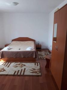 a bedroom with a bed and two rugs on the floor at Pensiunea IO-MARA in Vatra Dornei