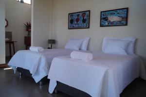2 camas en una habitación con sábanas blancas y toallas en Indano Art Lodge, en Lamas